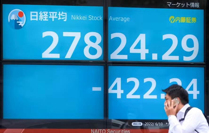 99510933-a-man-walks-past-an-electronic-share-price-board-showing-the-closing-numbers-on-the-tok