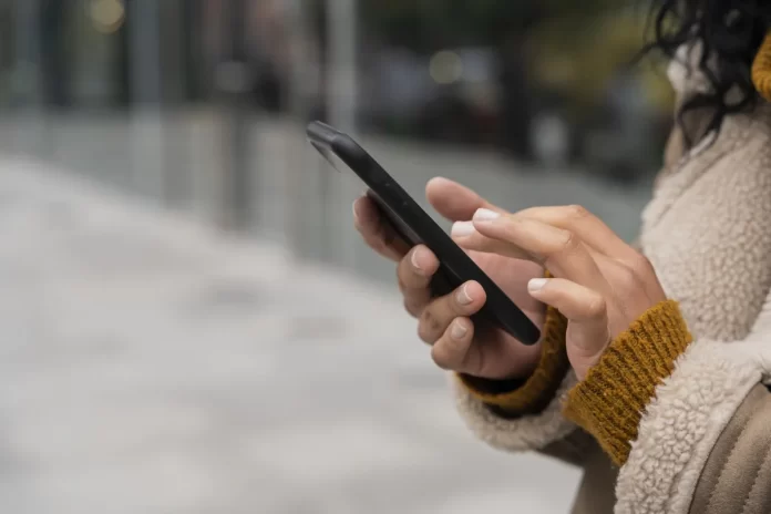 mulher-usando-seu-smartphone-lado-de-fora-com-espaco-de-copia